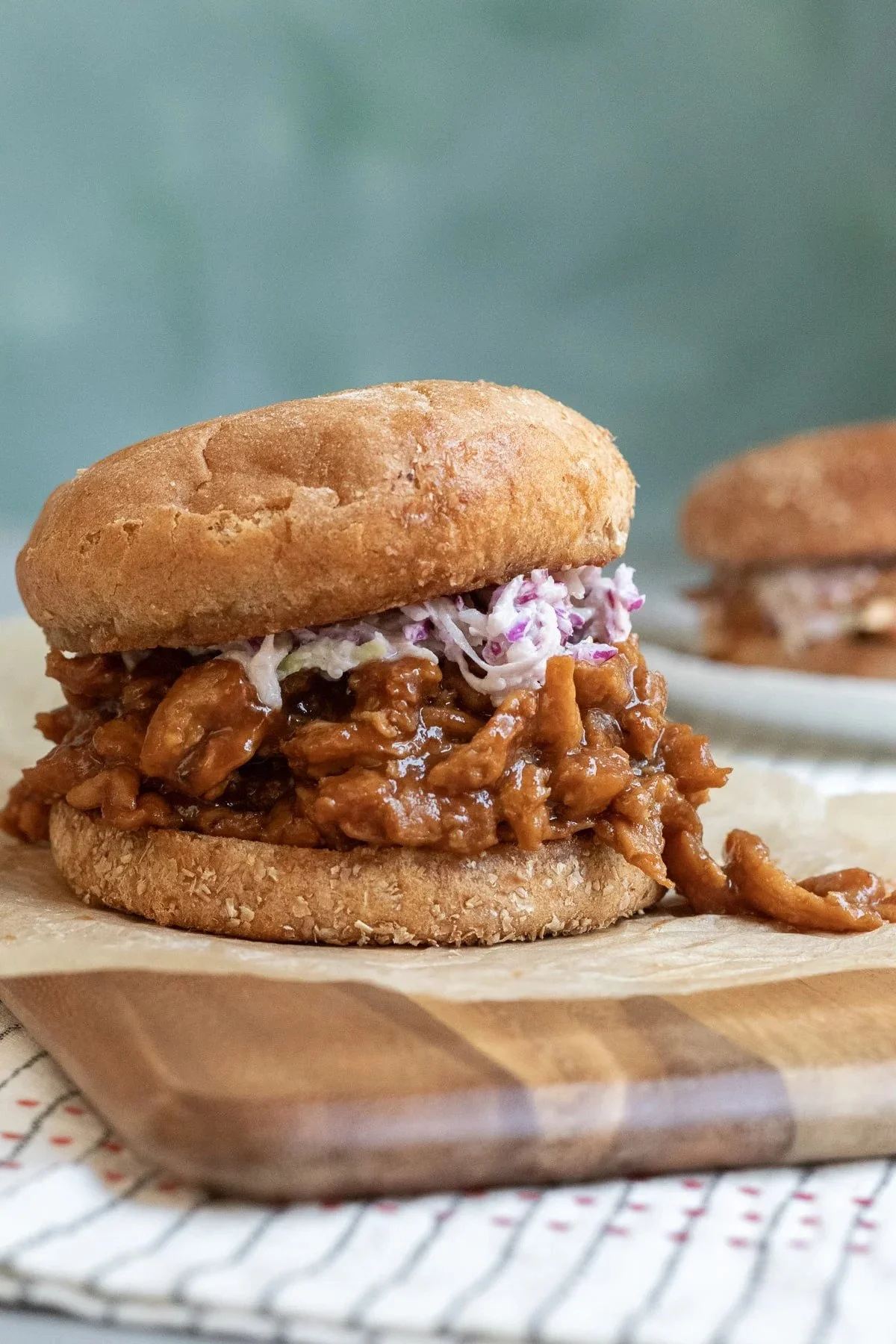 Barbecue pulled chicken sandwich with coleslaw in a whole wheat bun on a wooden serving board.