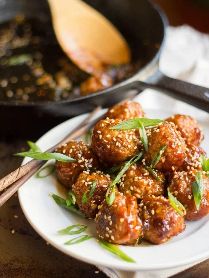 plate of teriyaki tempeh meatballs garnished with sesame seeds and green onion