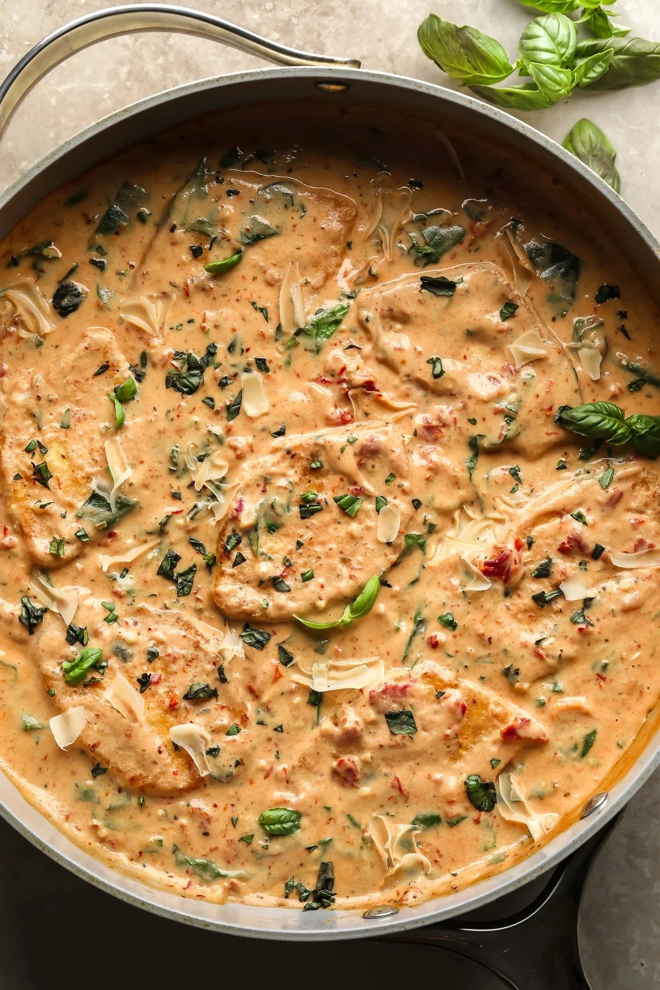 Creamy vegan vegetable curry garnished with fresh basil and shredded cheese in a skillet.