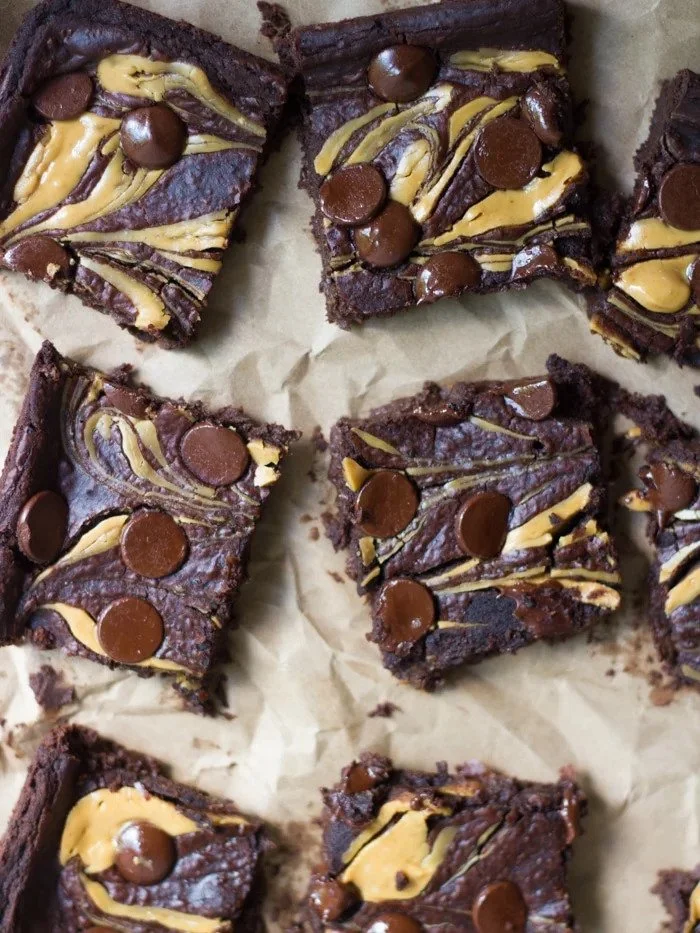 Squares of double chocolate brownies topped with peanut butter swirls and mini chocolate chips.