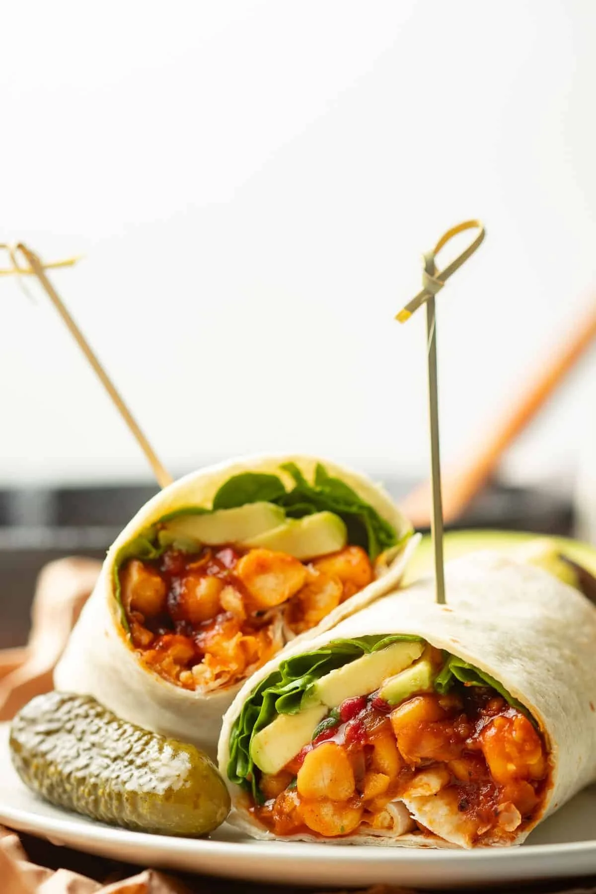 barbecue chickpea wrap cut in half with a pickle on the side
