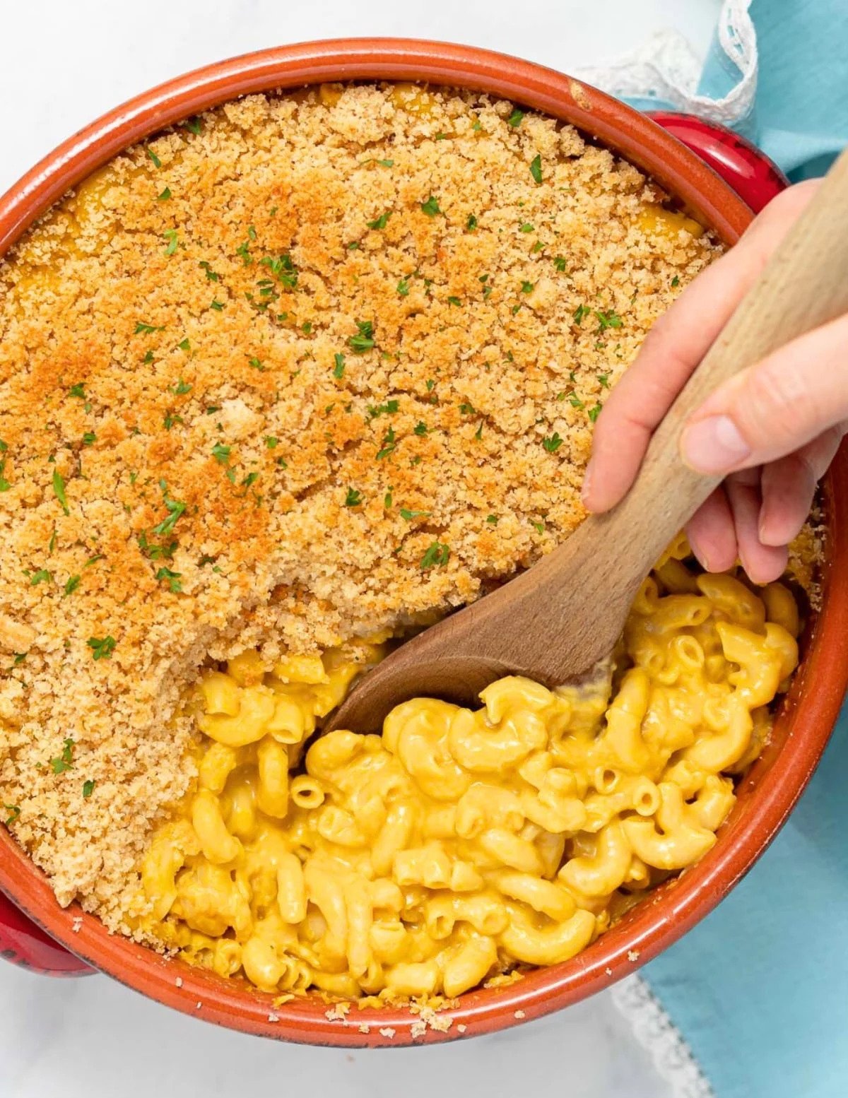 A bowl of macaroni and cheese with a breadcrumb topping and parsley garnish.