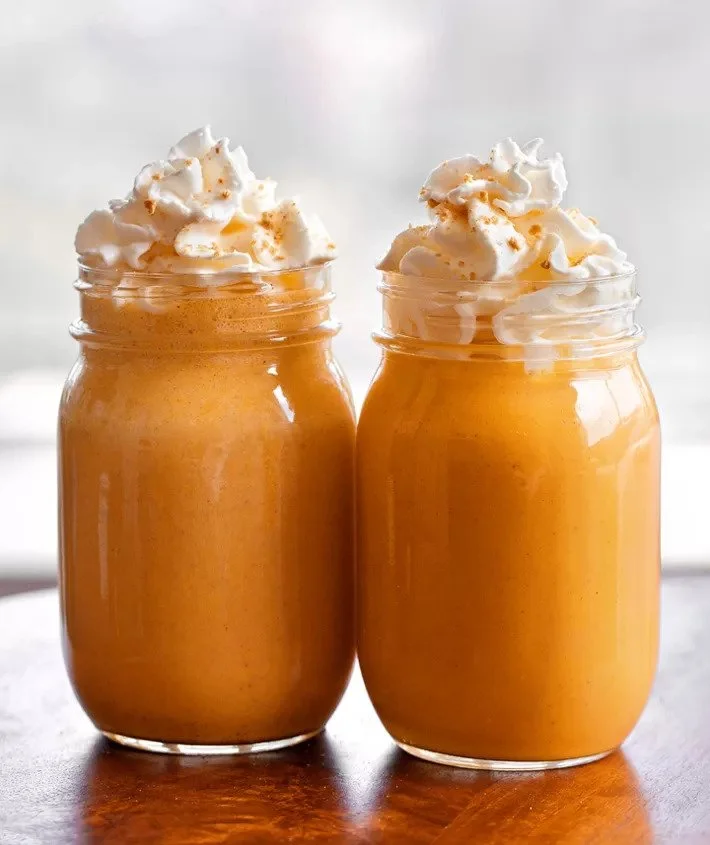 2 pumpkin pie smoothies in mason jars topped with whipped cream