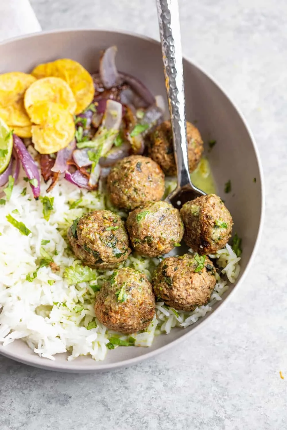Bowl of rice with falafel, chopped vegetables, and lemon slices.