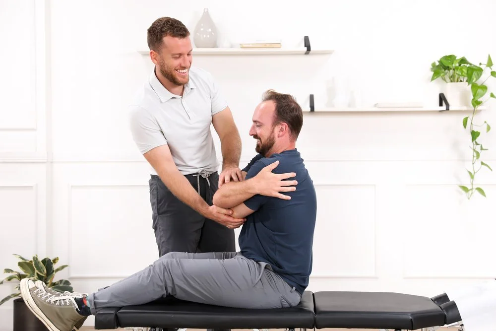 Dr. Yossi Stein setting up a mid-thoracic adjustment for a seated patient with arms crossed at Stein Chiropractic in San Diego.