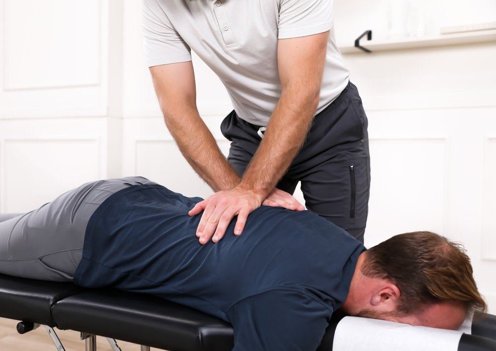 Dr. Yossi Stein delivering a hands-on spinal adjustment with the patient lying face down at Stein Chiropractic in San Diego
