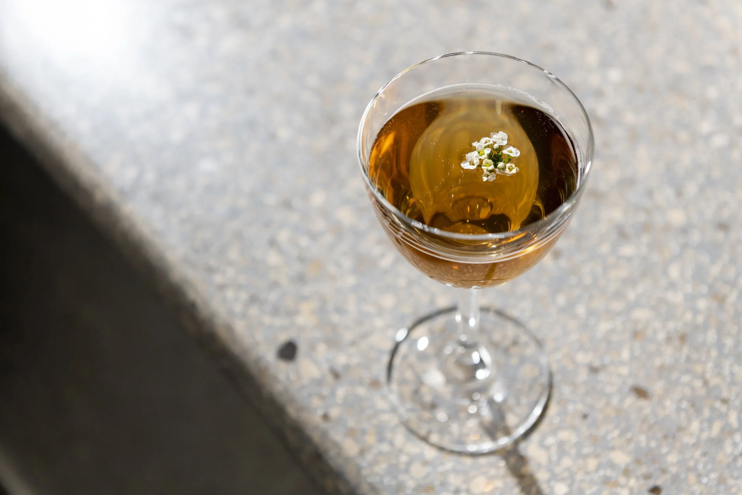 Atomix Cocktail Bar - Elegant Cocktail in a Coupe Glass with A Flower Garnish