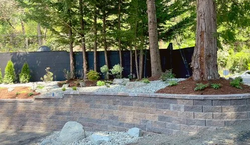 Mutual Materials Manor Stone retaining wall with accent boulders, dry river bed, mulch with plantings and trees