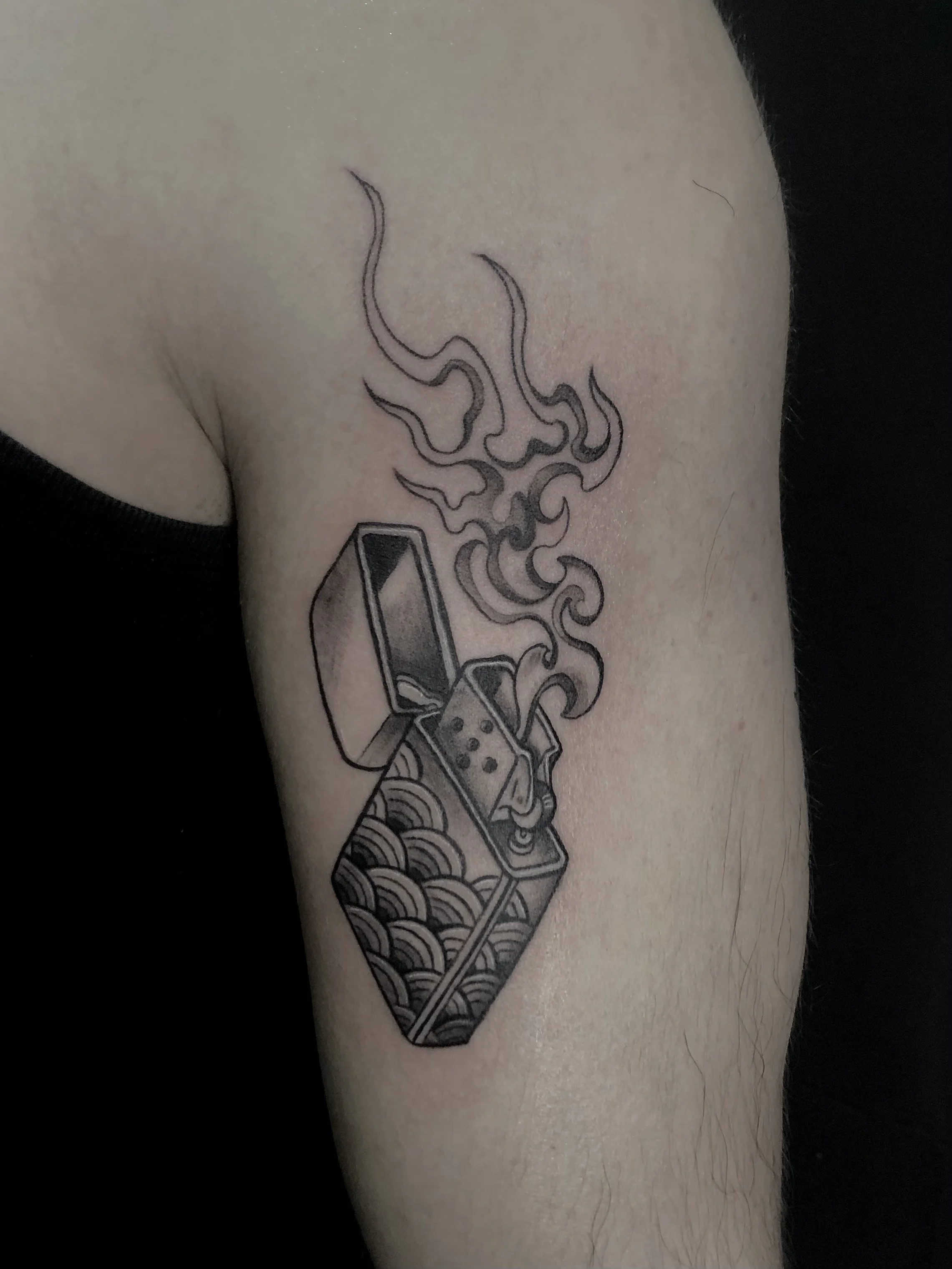 Tatouage représentant une cigarette avec de la fumée s'en échappant, sur le bras d'une personne.