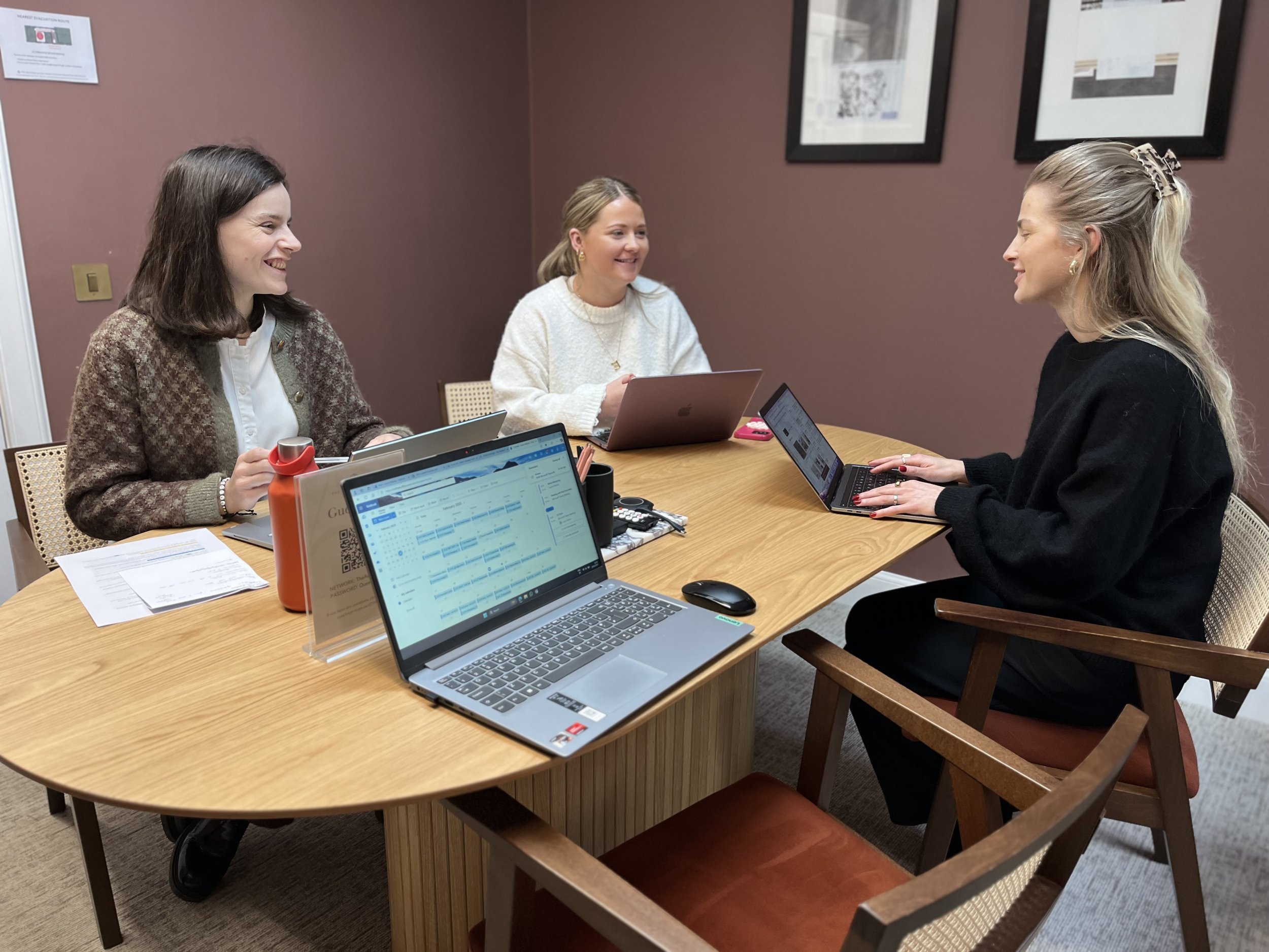 Meeting of 3 women in a brown meeting room. 4 laptops open on mid-century table. New Town Edinburgh Meeting space