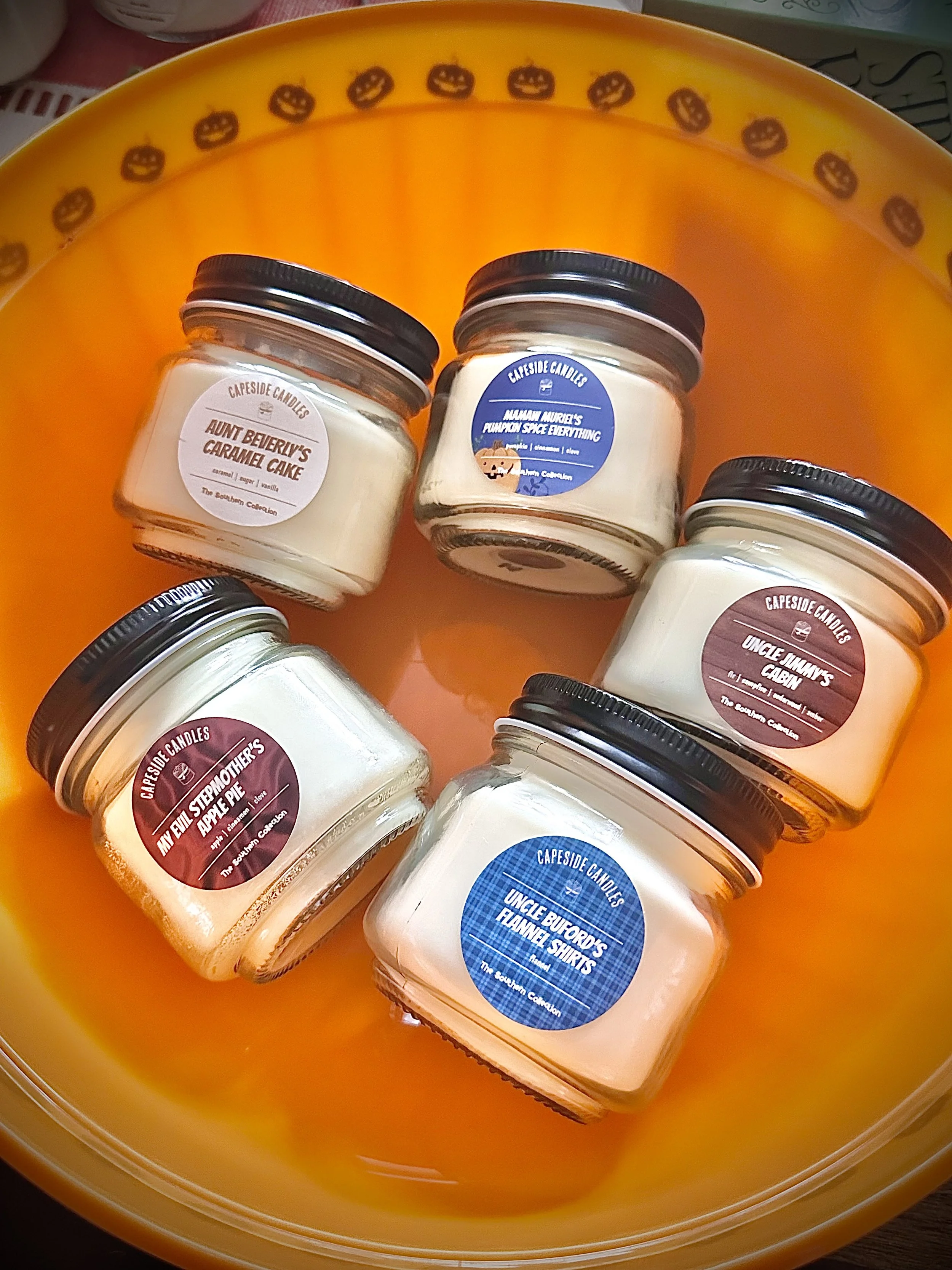 Summer and spring candles are displayed on a white rack. The candles are hand-poured in Wilmington, NC, and made with soy wax and fragrance and essential oil blends.