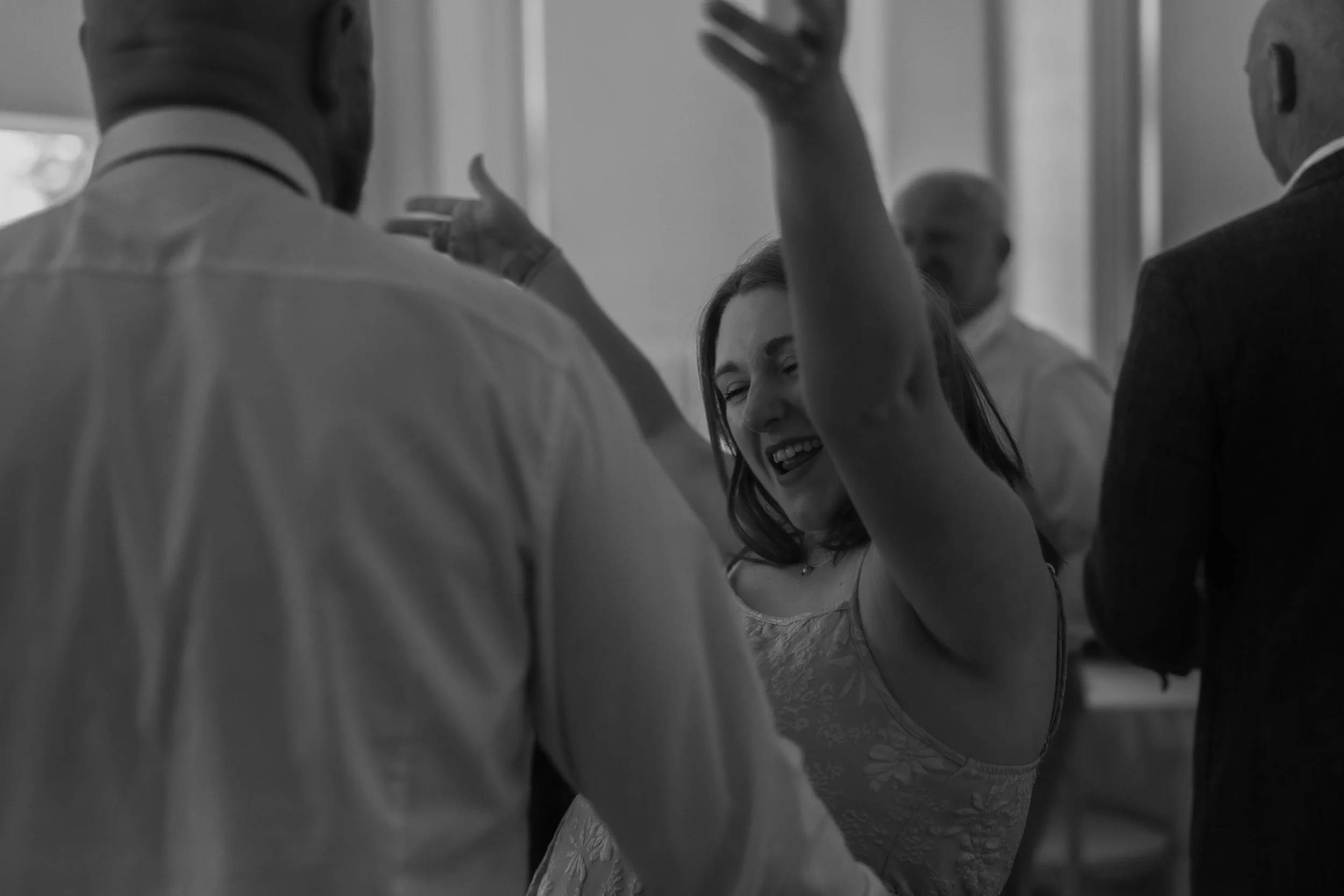 A woman dancing and smiling with others in a social setting.