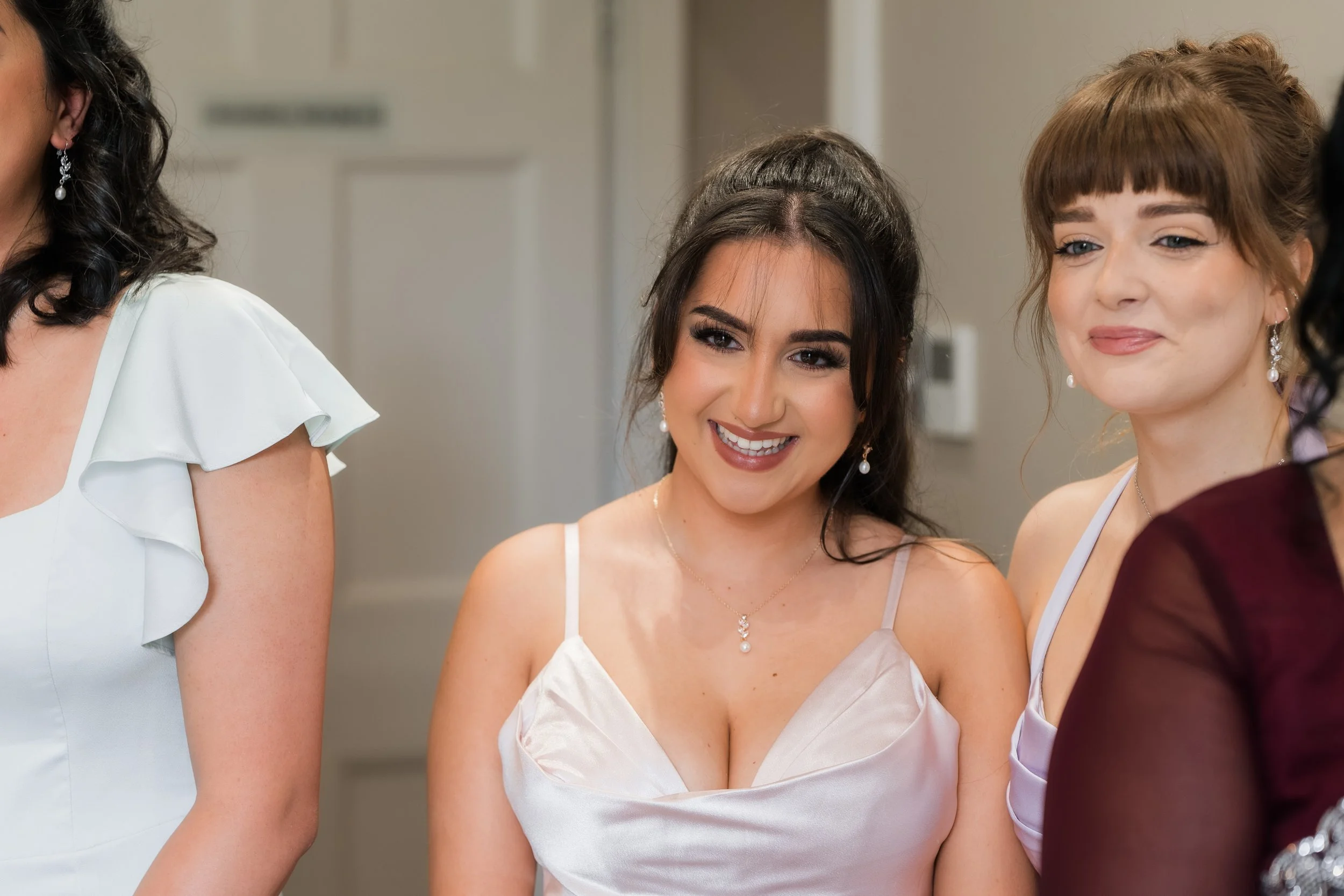 Two women smiling, dressed in formal attire, at what appears to be a festive event.
