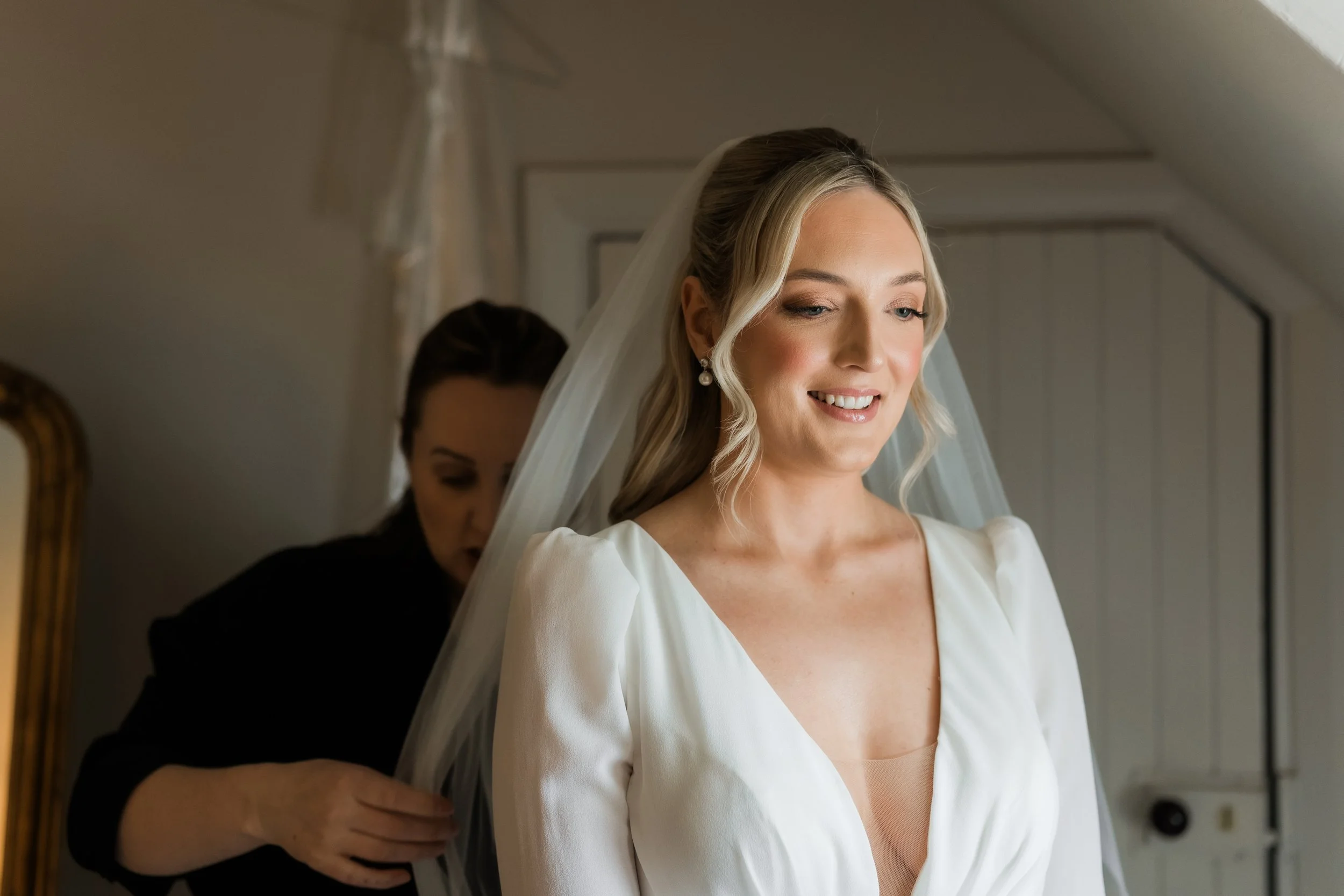 Unposed shot of the bride adjusting her dress, framed in soft, elegant tones