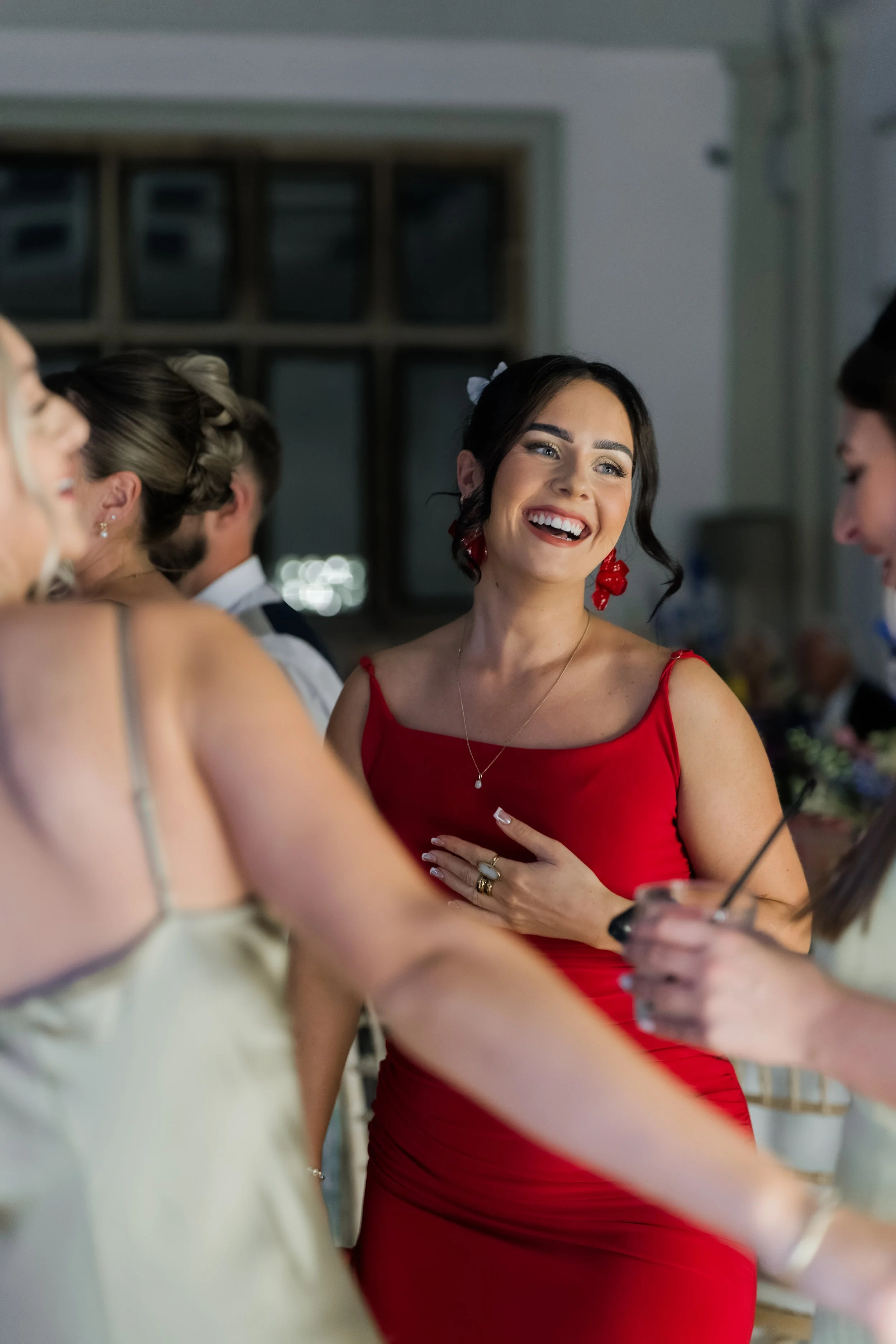 A woman in a red dress smiling and engaging with others at a social gathering.
