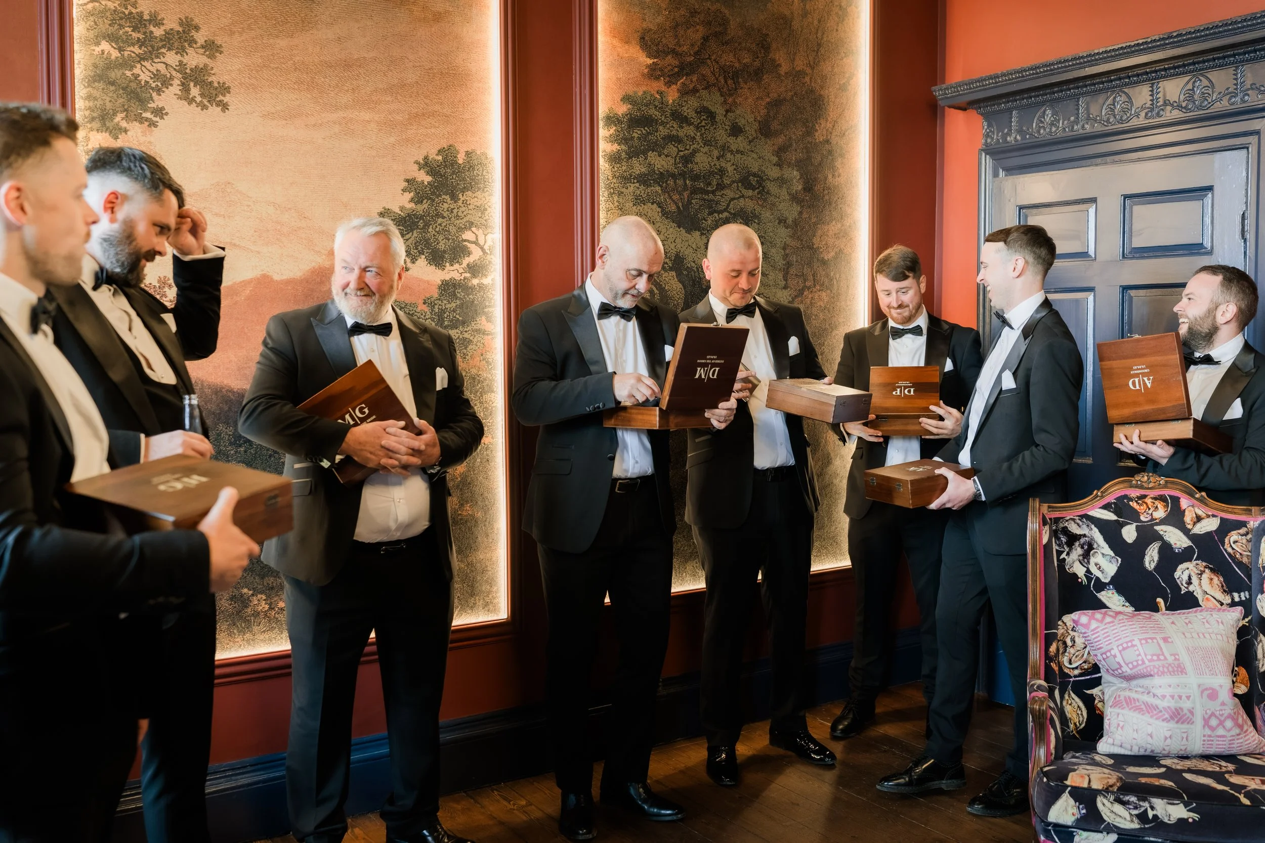 Unposed interaction between the groom and his groomsmen during gift exchange at Charlton Hall