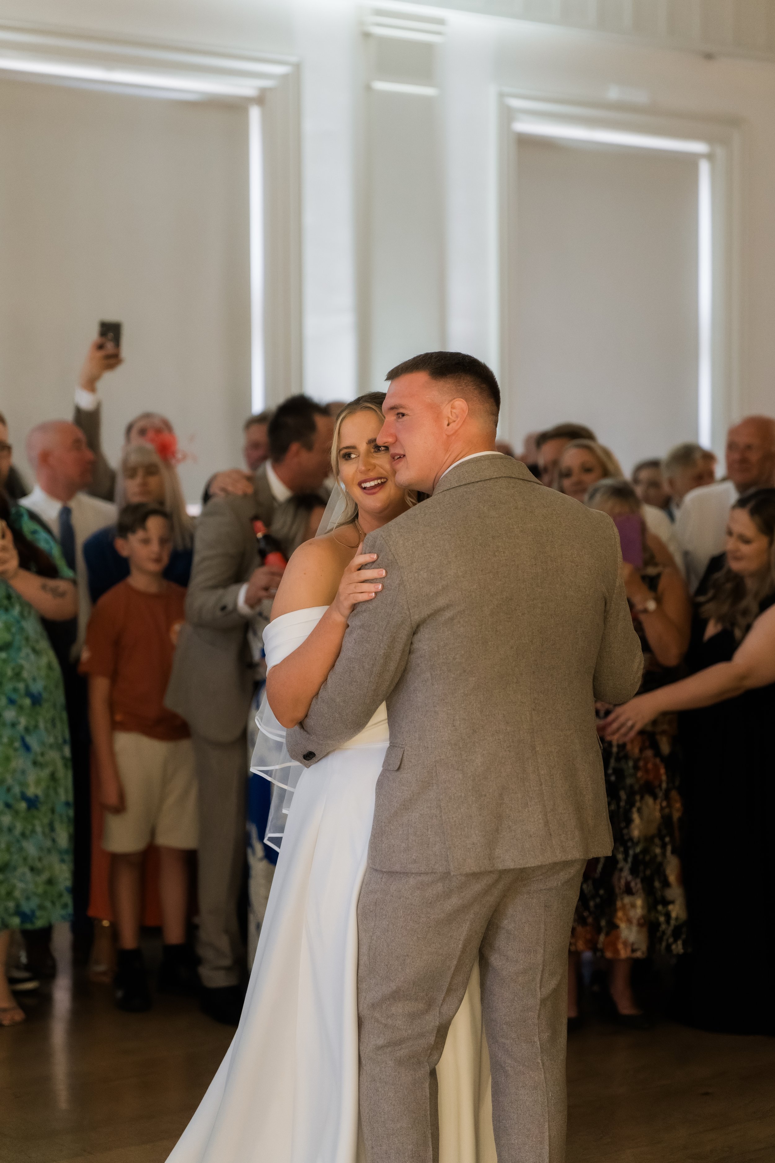 Bride and groom dancing during their wedding reception with guests watching in the background.