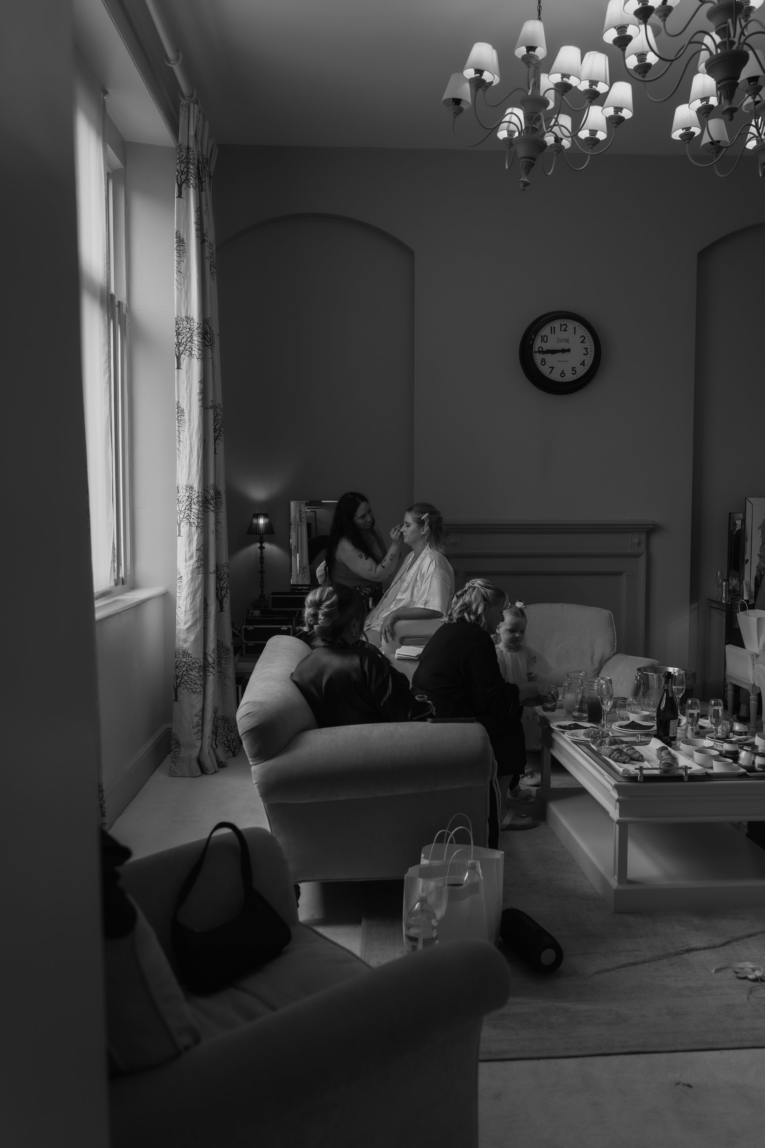 L&J Wedding Photography & Videography. Documentary Yorkshire Weddings. Wider shot of room during bridal prep. bridemaid talking in forground. Bride having make up done in background