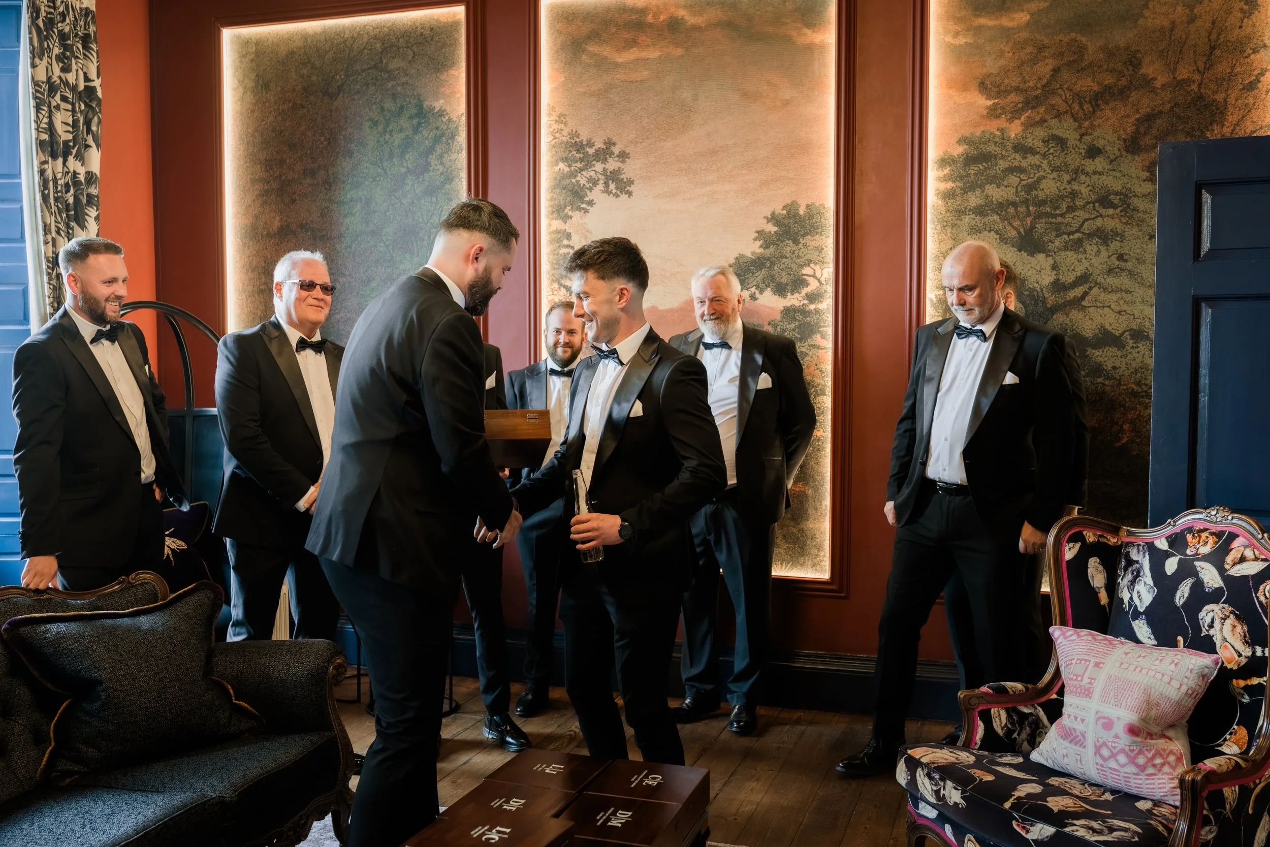 Groom sharing a quiet moment with his groomsmen while giving thank-you gifts before the ceremony