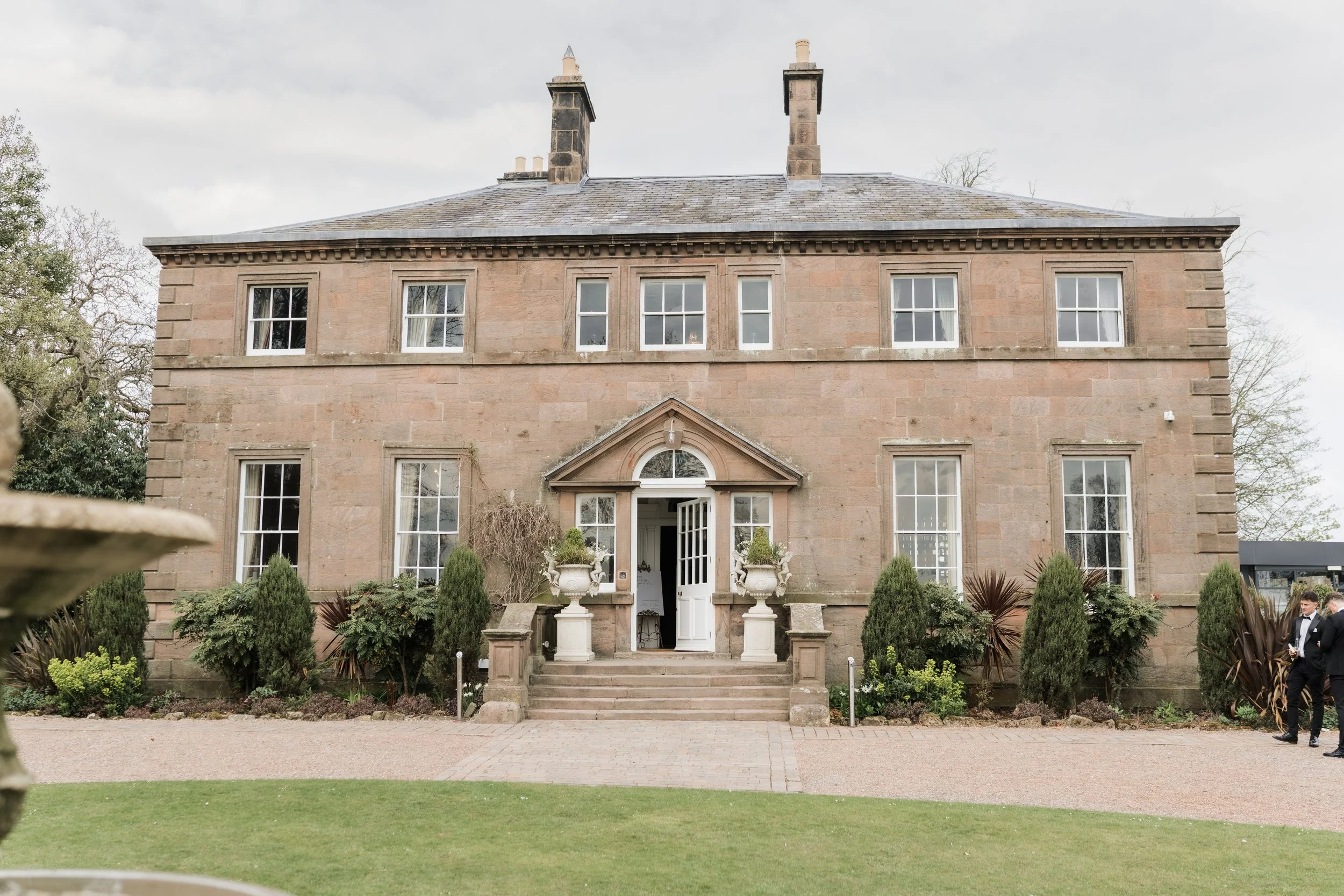 Exterior view of Charlton Hall’s main building on a wedding day, surrounded by lush grounds and dramatic skies