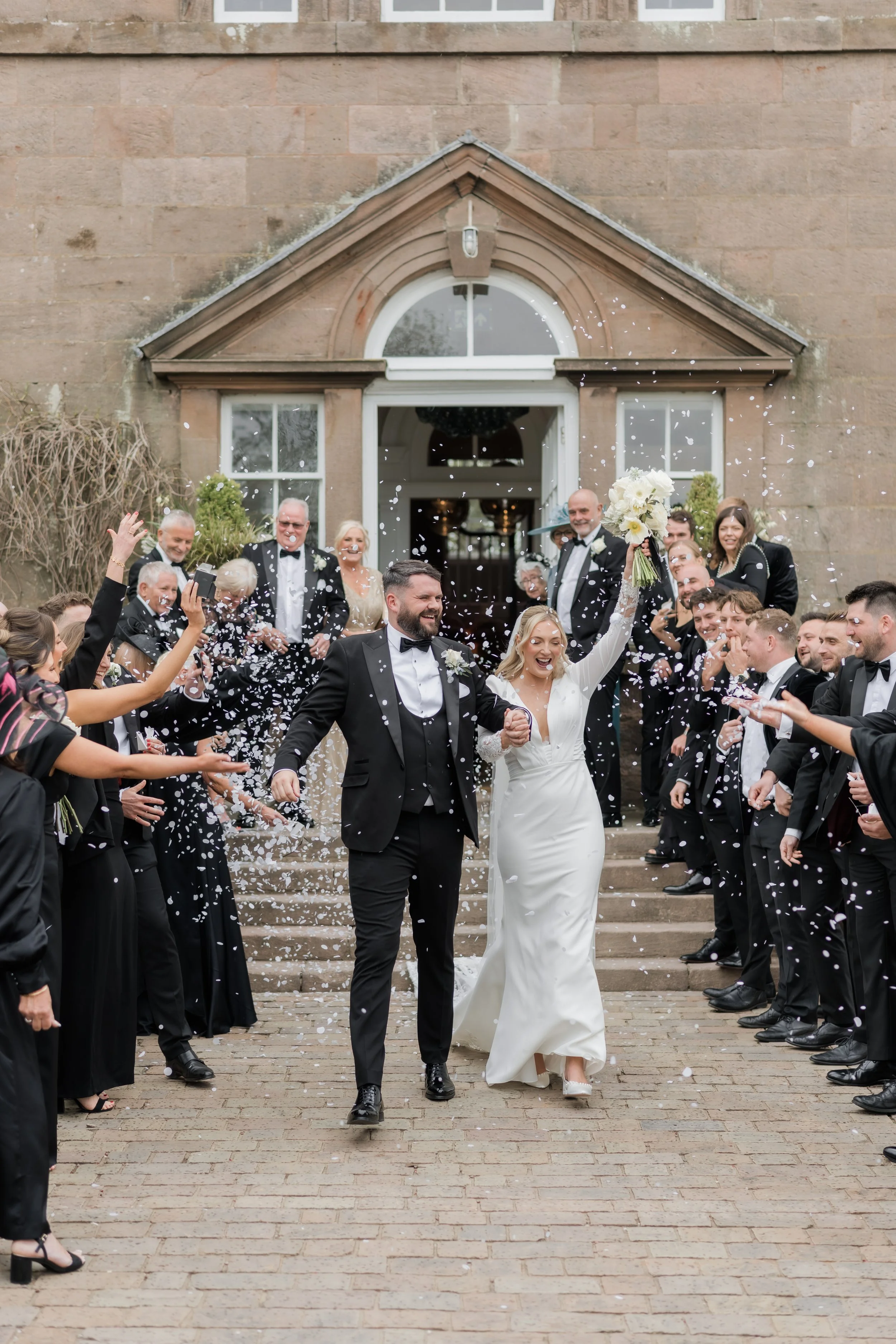 Confetti throw outside Charlton Hall, with the newlyweds smiling and surrounded by celebration
