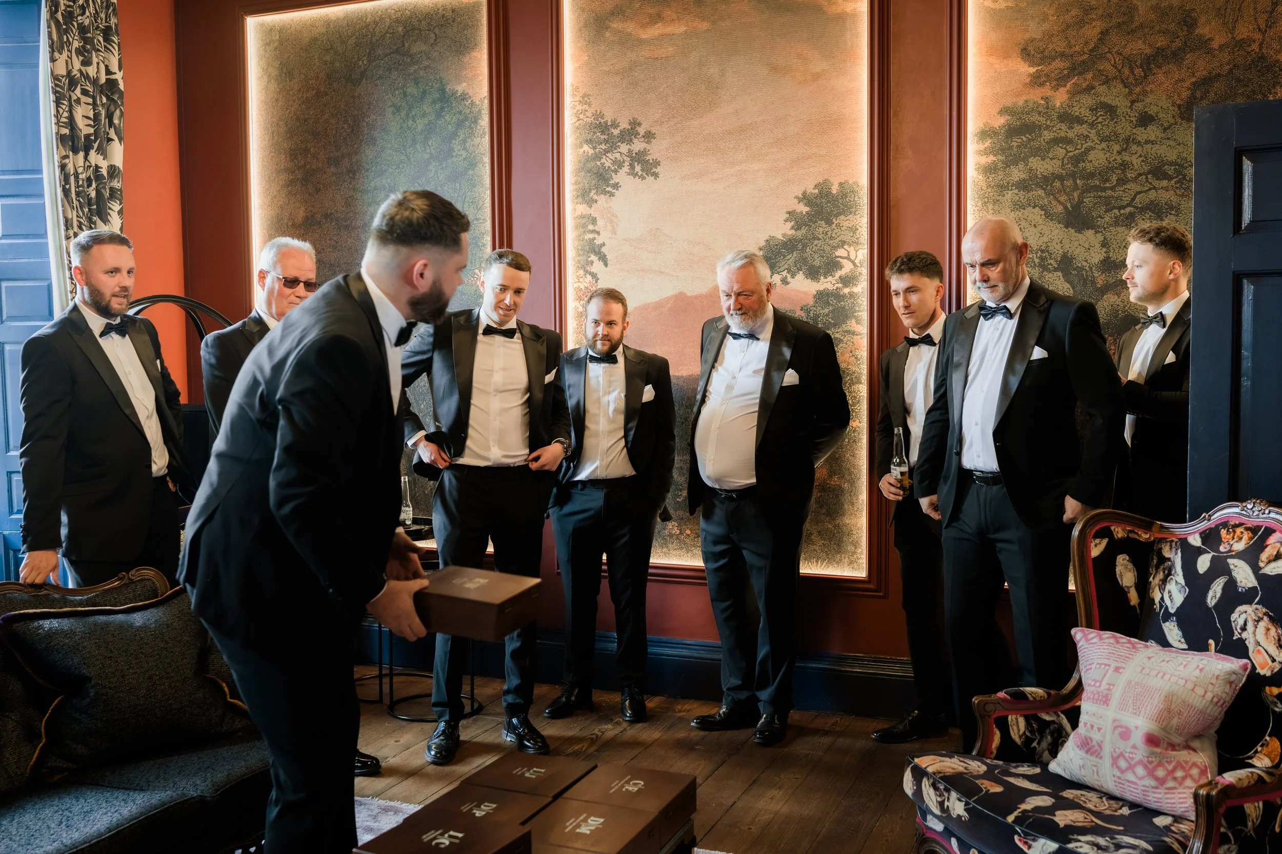 Candid moment of the groom handing gifts to his groomsmen on the wedding morning at Charlton Hall