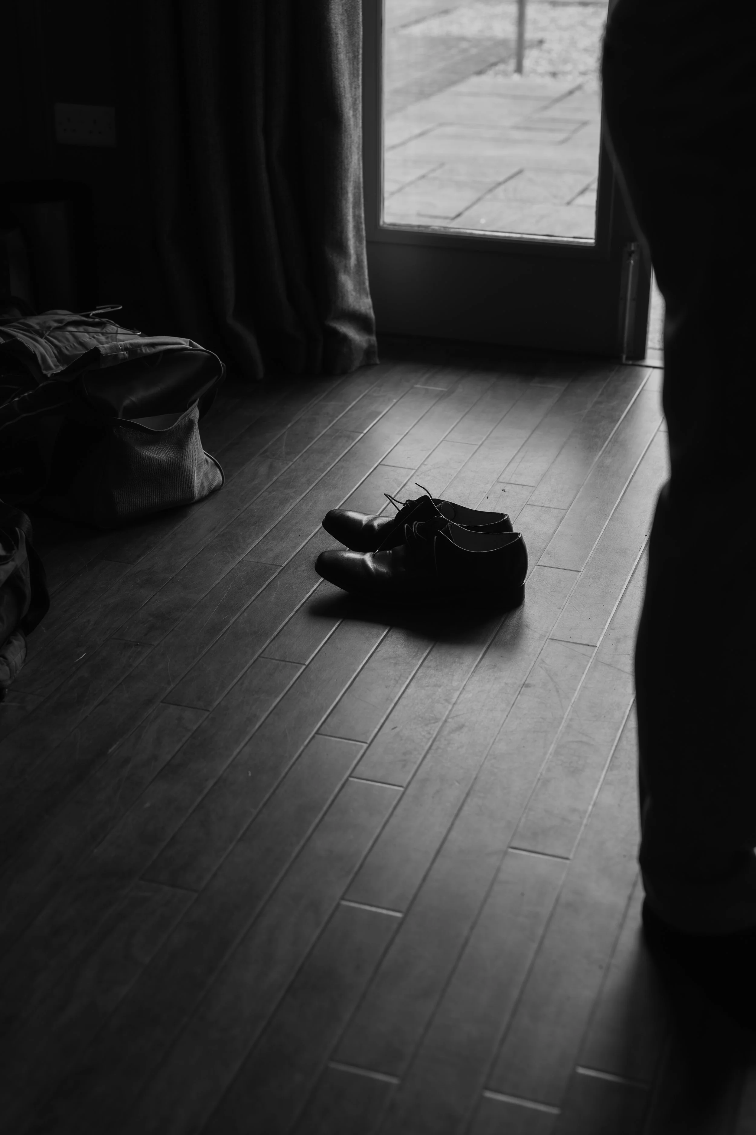 Grooms shoes lie on floor in shaft of light