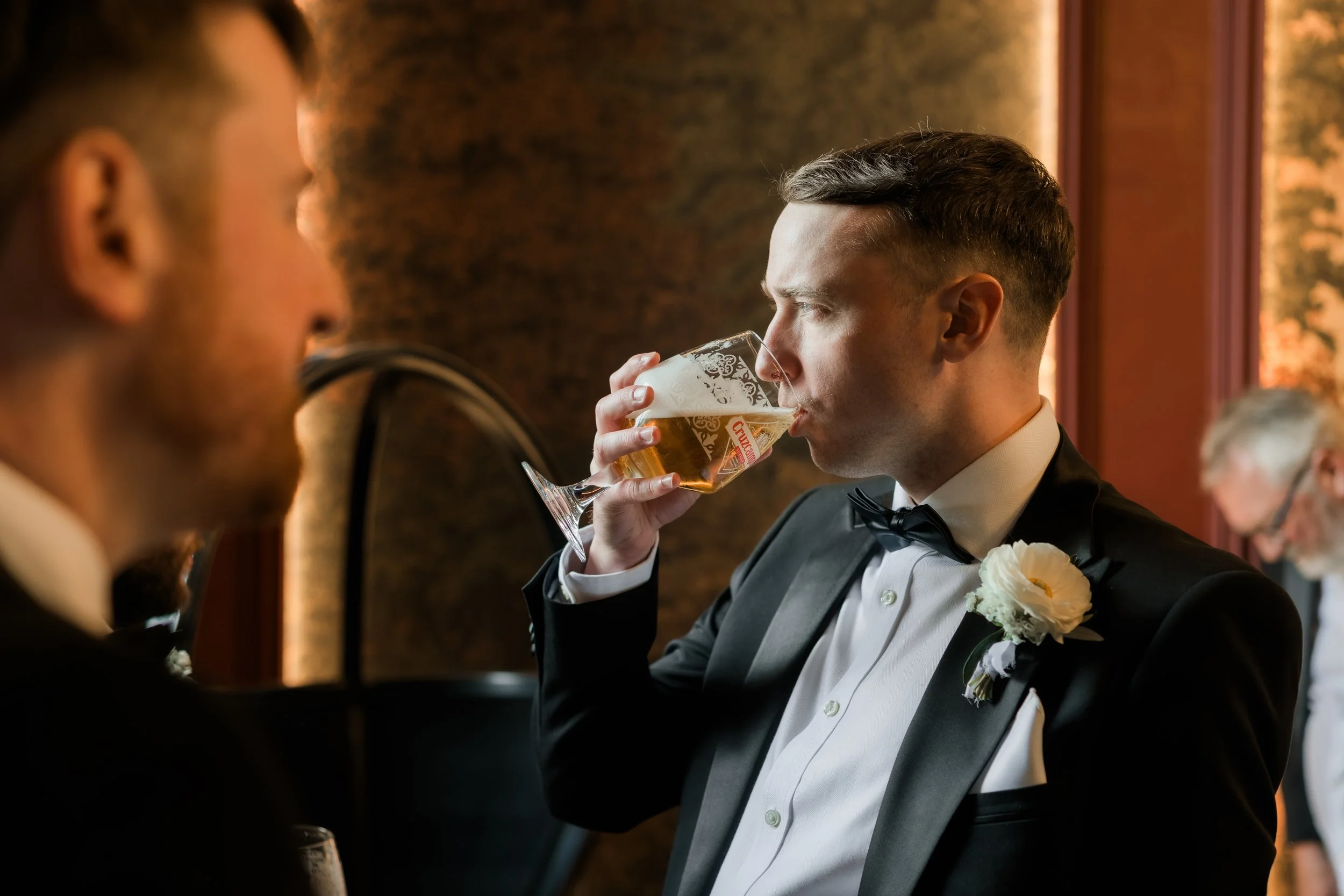 Documentary moment groom drinks with groomsman natural light