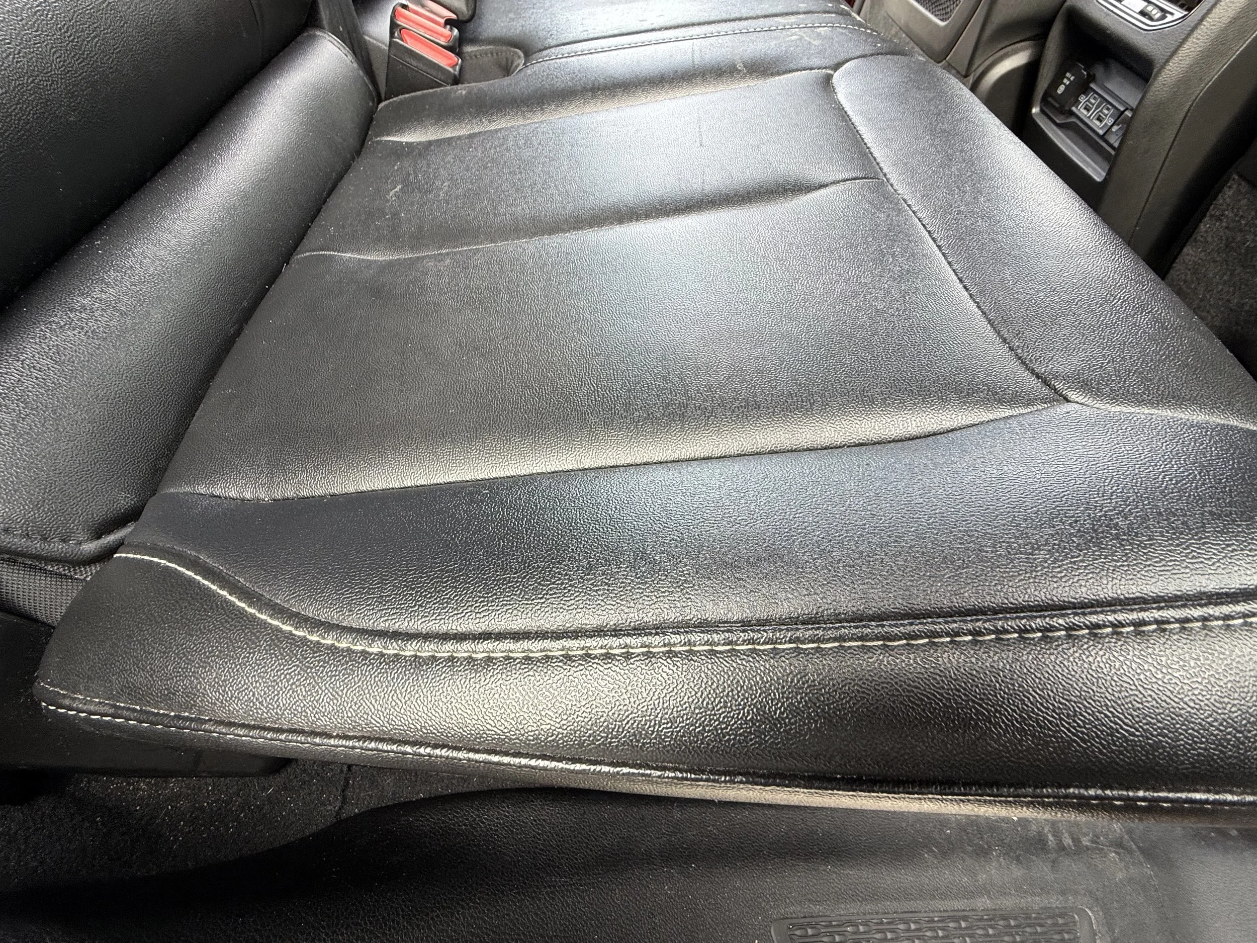 Close-up of black leather car seat with visible stitching and texture.