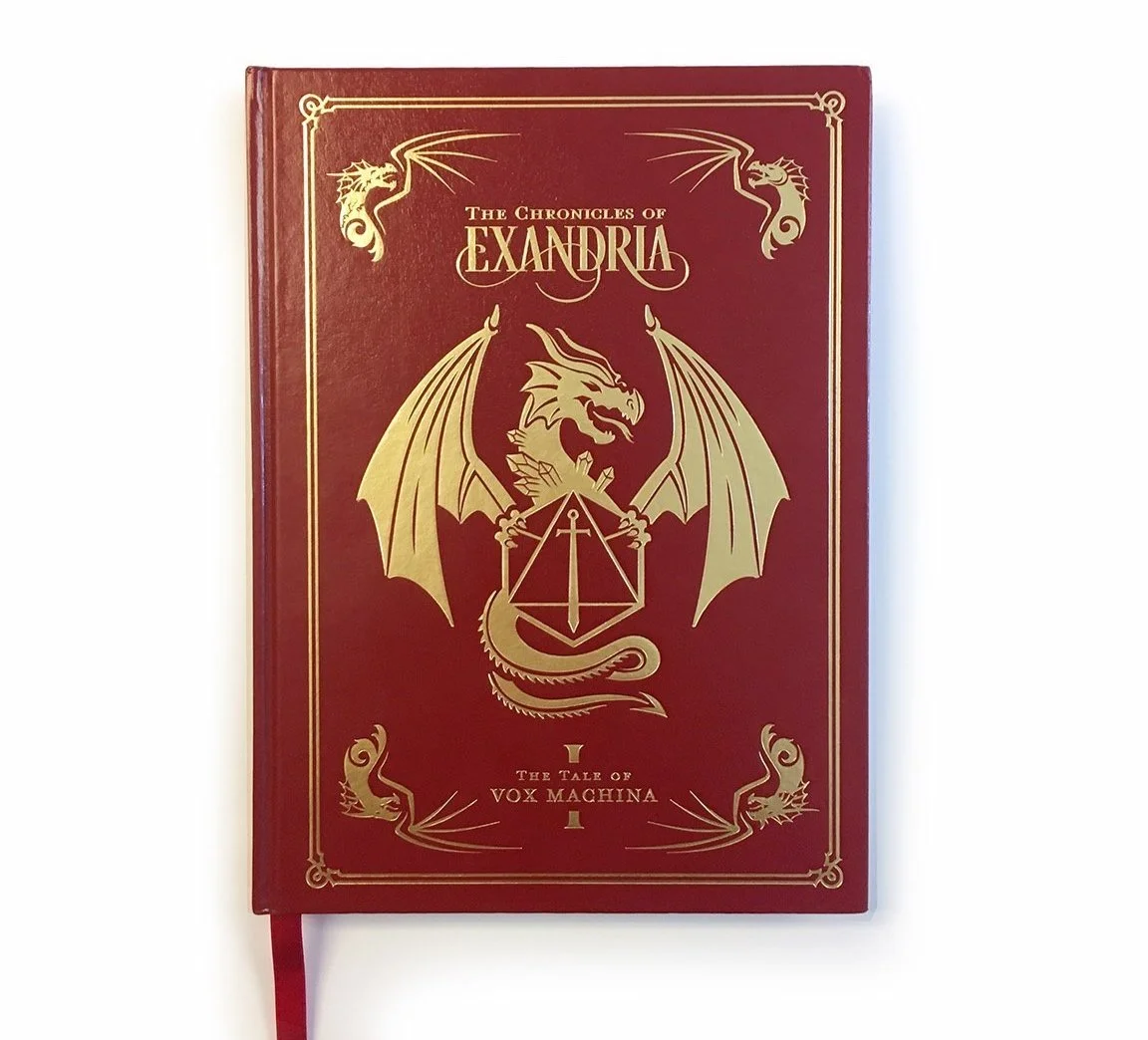 Red hardcover book titled 'The Chronicles of Alexandria: The Tale of Vox Machina' with gold foil dragon and sword emblem on the cover.