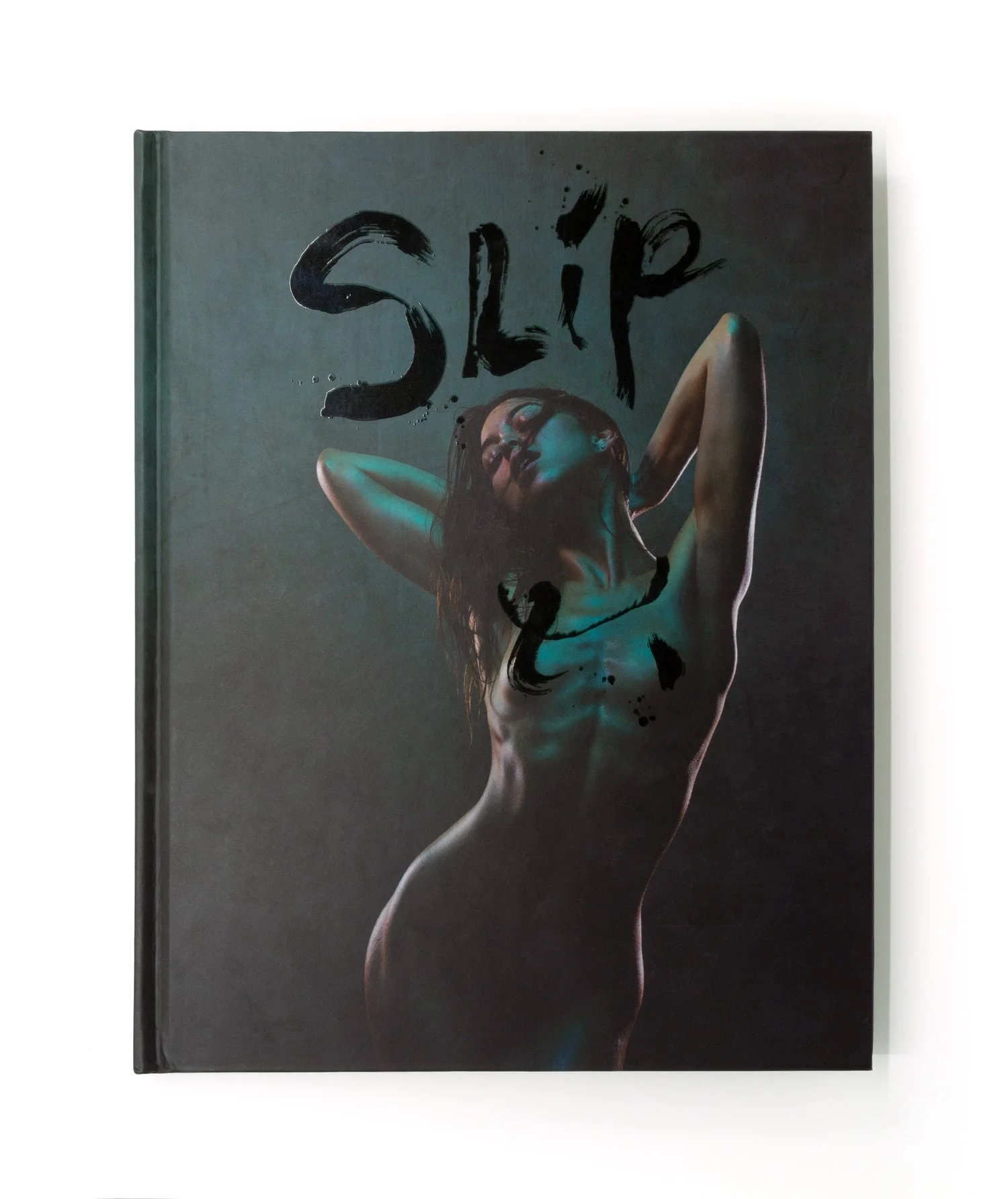 The text of this book cover reads "SLIP" in brush lettering. The cover art is a photograph of a petite nude woman with brown hair. Her arms are reaching behind her. The background is teal and teal shadows reflect on the woman.