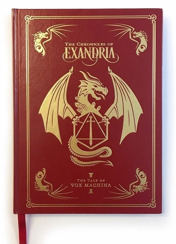 Red faux leather deluxe cover of Critical Role: “The Chronicles of Exandria Vol. I: The Tale of Vox Machina,” with a debossed gold foil dragon framing the Critical Role logo (a sword and twenty-sided die) and four smaller dragons in the corners.