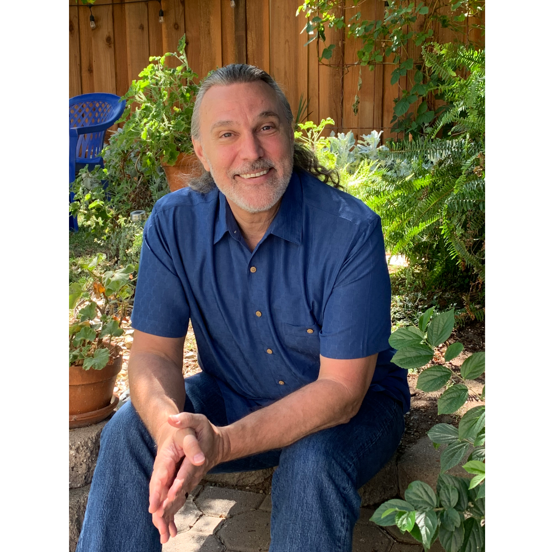 Portrait of Eric Winton seated outdoors, smiling warmly.