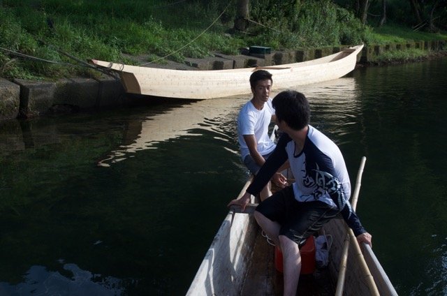 The new owner motors away from the boat as an apprentice takes a last look.