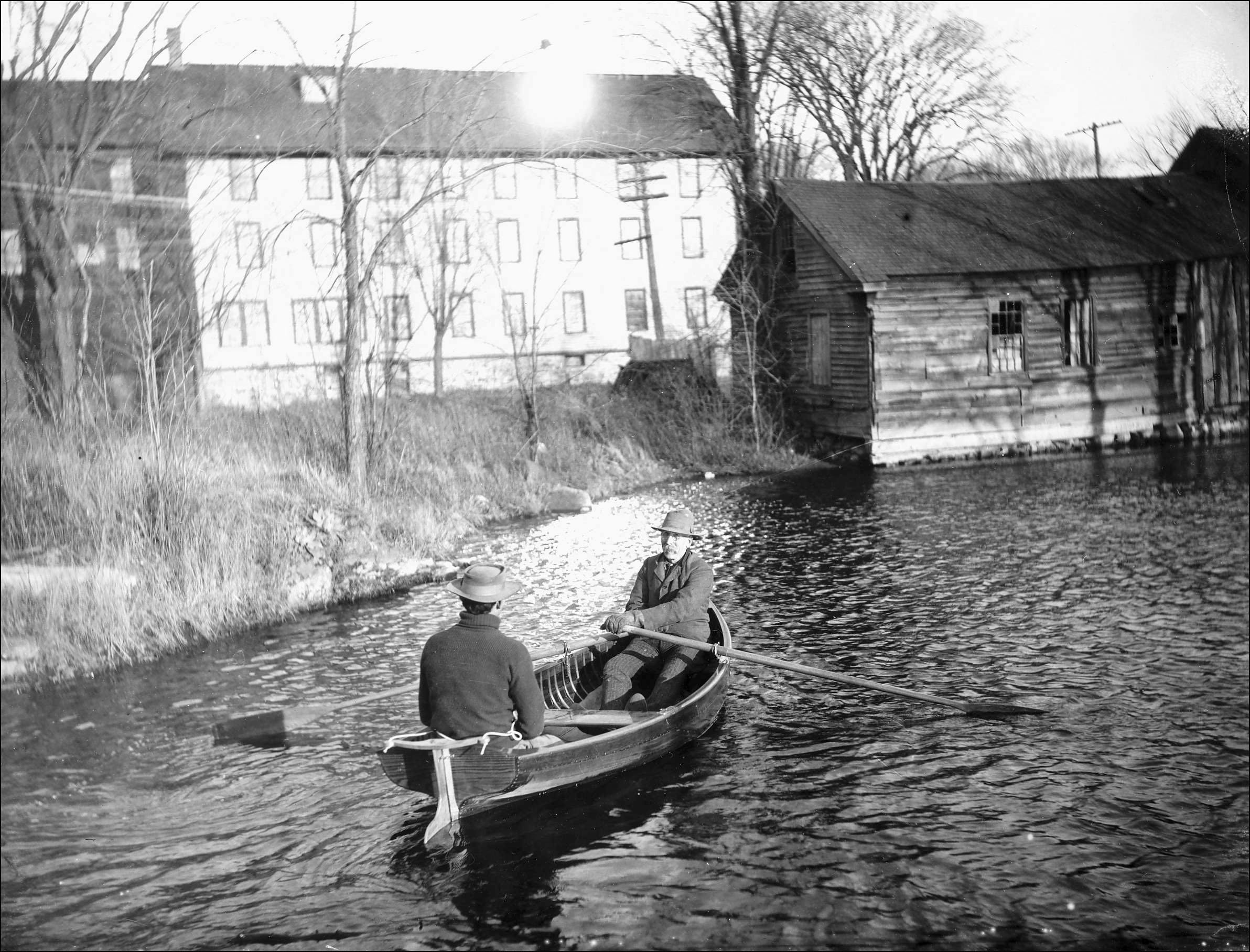 The dinghy being rowed with the Rushton factory in the background. Courtesy of the St. Lawrence County Historical Society.