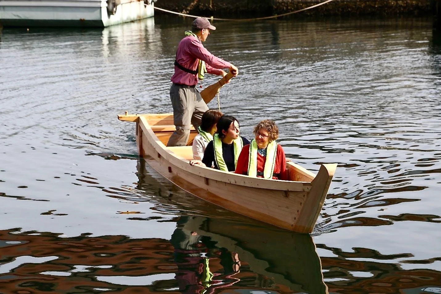Douglas Brooks sculling a traditional Japanese wooden Isobune with passengers, built for the Takenaka Carpentry Tools Museum.