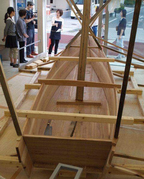The planks are shown supported by temporary braces, posts and various props, typical of the Japanese boat shop.