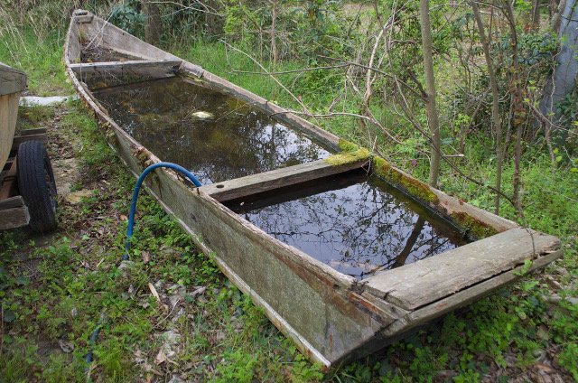An eight meter ayubune, fiber-glassed and derelict near the river.