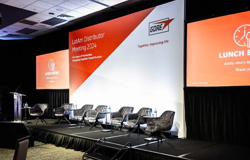 Breakout stage with printed backdrop, projection screens, chairs, and podium