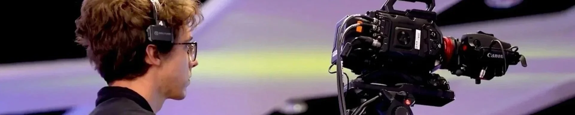 Camera technician operating a tripod camera for event video production and onsite crew support