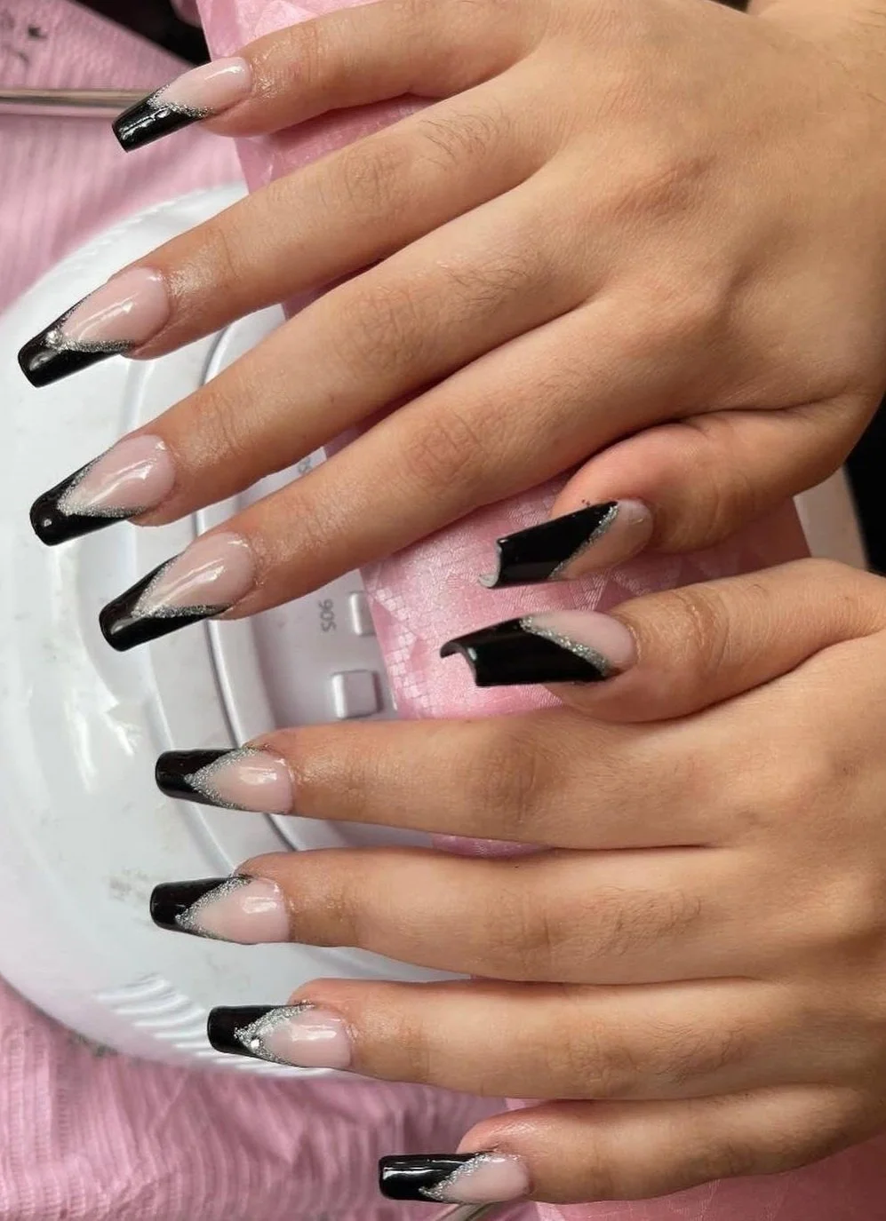 Close-up of hands with black and nude ombre French manicure.