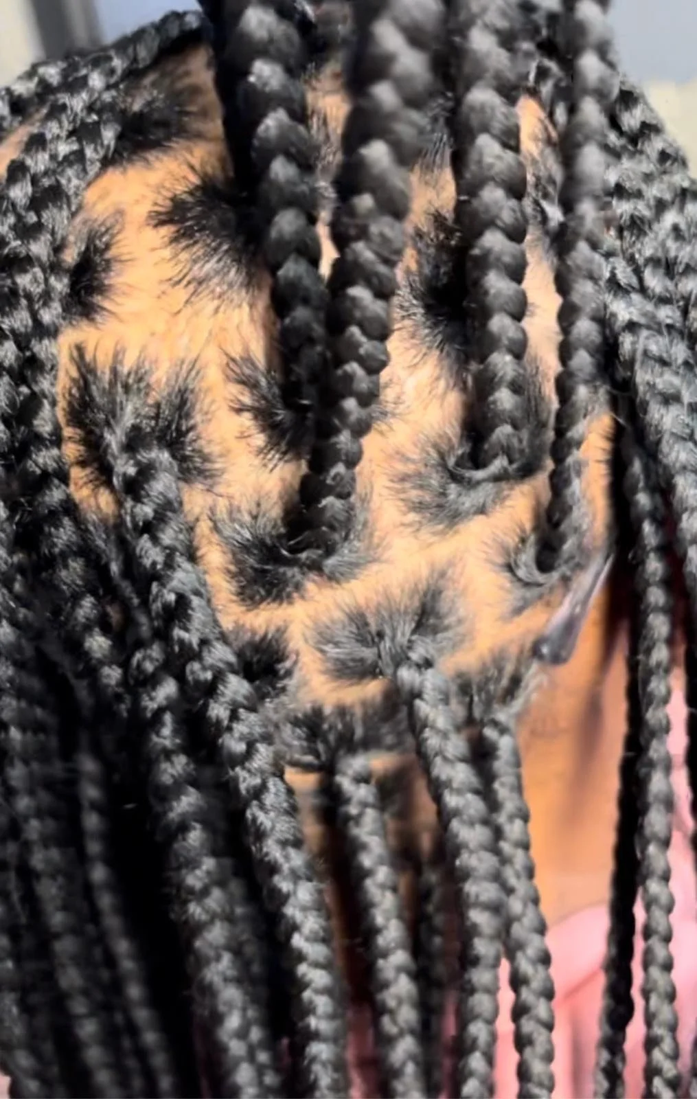 Close-up of a person's forehead with multiple long, black braids covering their face.