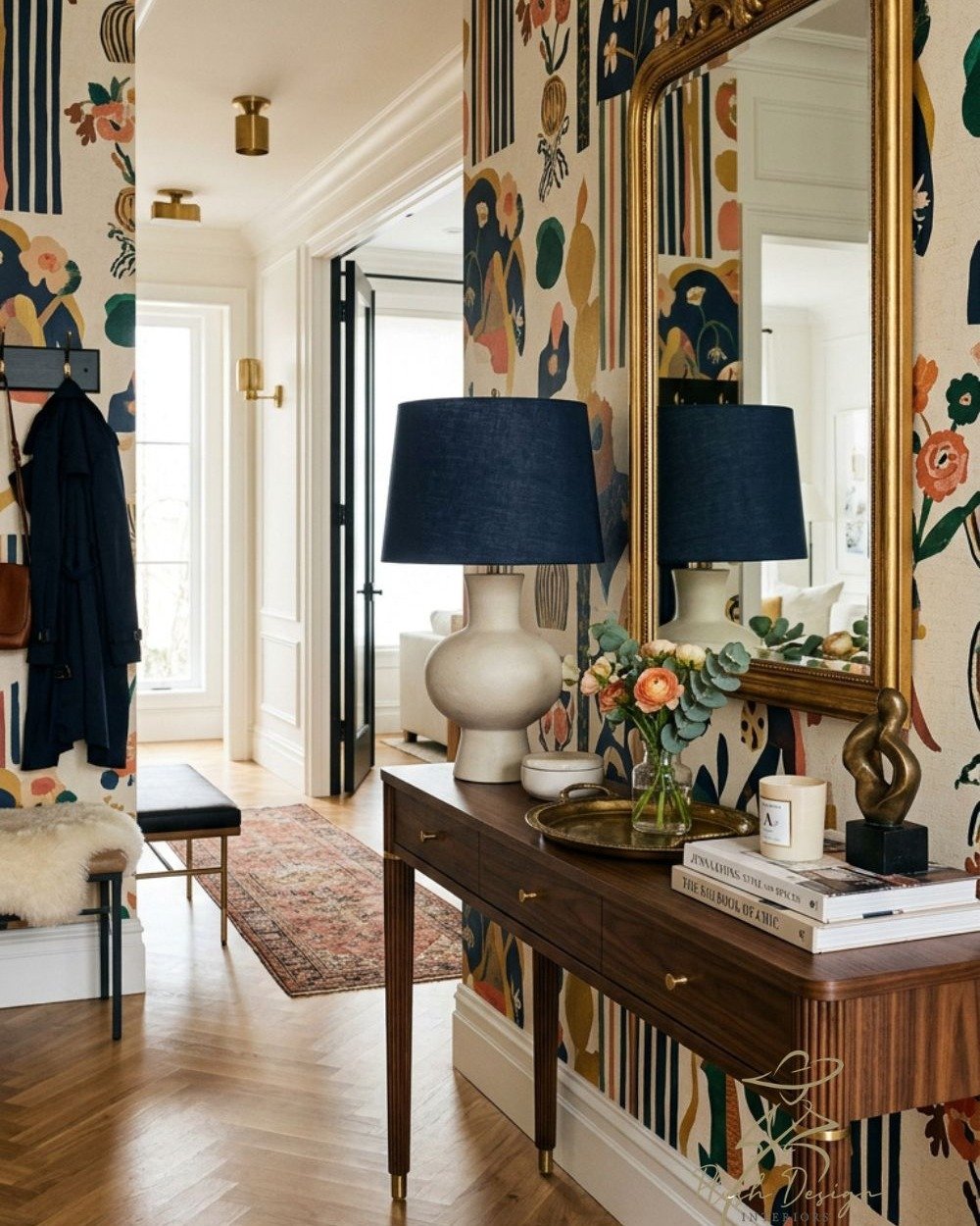 Use bold wallpaper in your entry but keep other items calm, such as the blue lampshade and herringbone wooden floor. The biedermeier-style console table and regency-style mirror work well with a bold patterned wallpaper because they are not 'fighting
