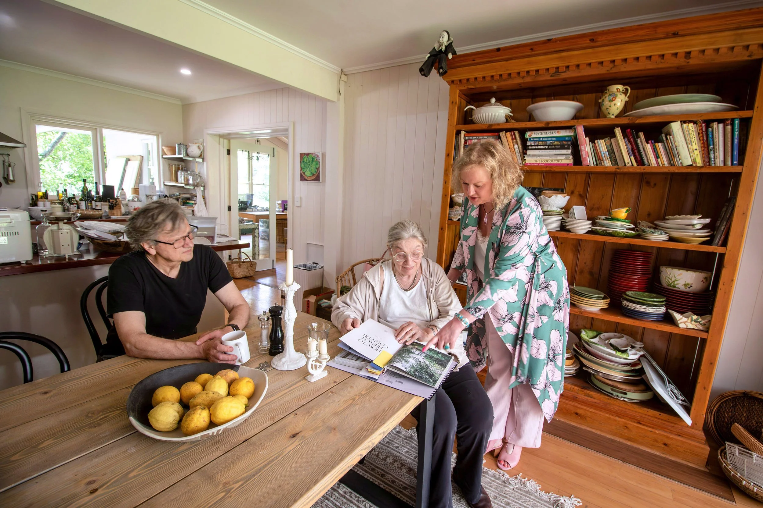 Clients and an interior designer from Plush Design Interiors discussing renovation plans in a partially demolished kitchen with exposed brick wall.