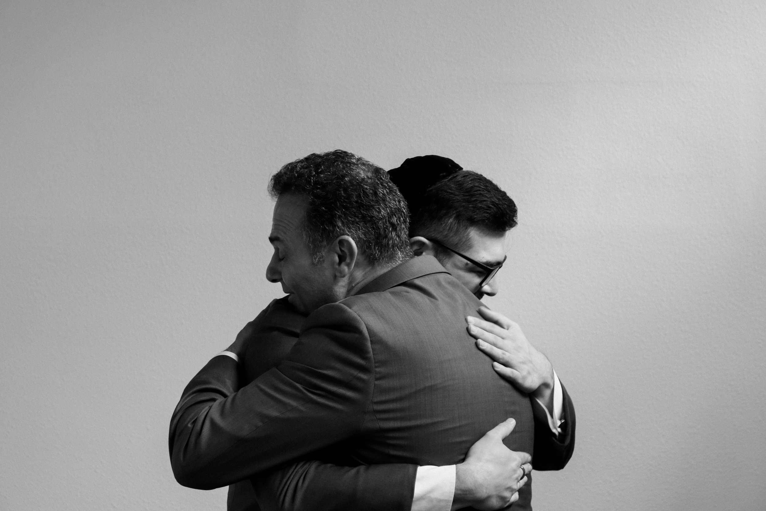 Two men in suits hugging each other in a black and white photo.