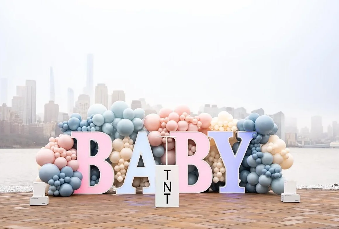 Baby marquee letters with balloons decoration and TNT box for gender reveal, with New York City sky line view.
