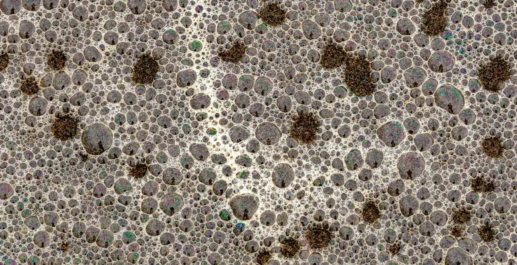 Surf froth on beach sand with reflections captured by Raj Sarda Photography