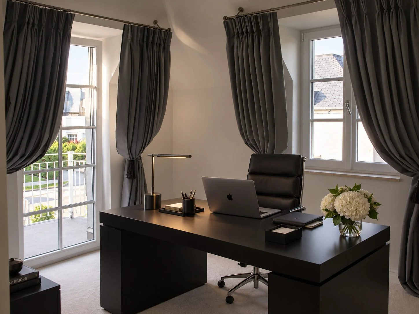Elegantes Homeoffice mit schwarzem Schreibtisch, Leder-Bürostuhl, dunklen Vorhängen und stilvoller Beleuchtung.