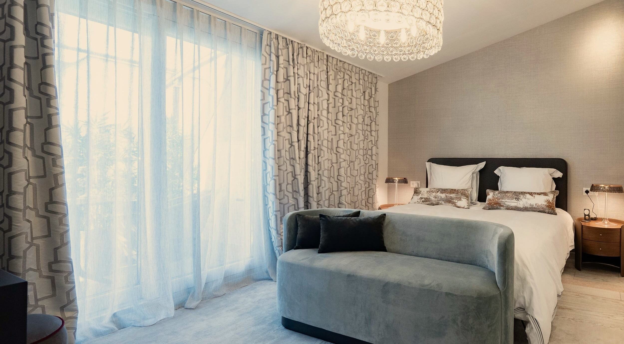 Main Bedroom des Rooftop Apartments mit gepolstertem Bett, hellblauer Sitzbank, maßgefertigten Vorhängen und strukturierter Wandgestaltung.