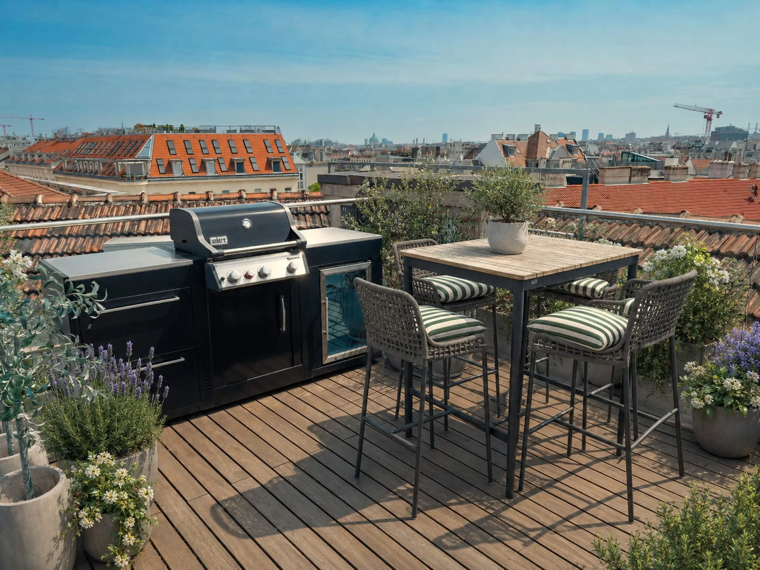 Gestalteter Grill- und Essbereich auf der Dachterrasse mit Outdoor-Küche, Hochtisch, gepolsterten Stühlen, mediterraner Bepflanzung und Blick über Wien.
